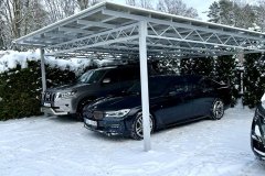 Навес для авто на металлическом каркасе с поликарбонатной крышей на парковке у дома.