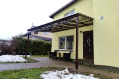 Односкатный навес для дома из поликарбоната на металлическом каркасе с зоной отдыха у входа.