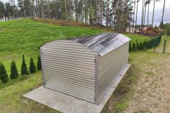 Saimniecības bloks no metāla profila ar arkveida jumtu un vārtiem teritorijā